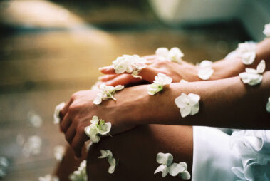 woman's hands and arms with white flower petals resting on skin