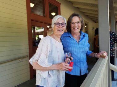 Close up of two smiling guests holding wine glasses on the porch