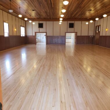 Large main hall with lights shining on restored hard wood floors