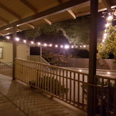 Porch at night with lights strung across courtyard